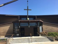 Exterior photo of metal cross installation on church roof